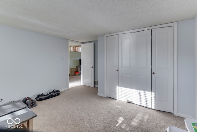 unfurnished bedroom featuring light colored carpet, a textured ceiling, and a closet