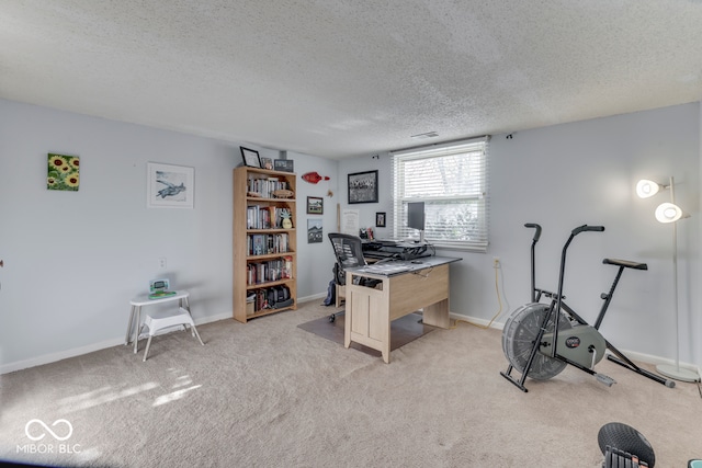 carpeted home office featuring a textured ceiling