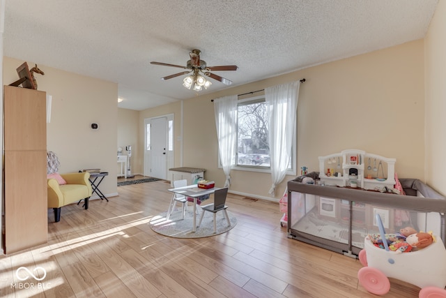 interior space featuring ceiling fan, a textured ceiling, and light wood-type flooring