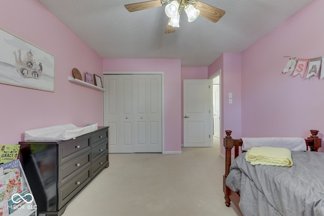 bedroom featuring ceiling fan, light colored carpet, a textured ceiling, and a closet