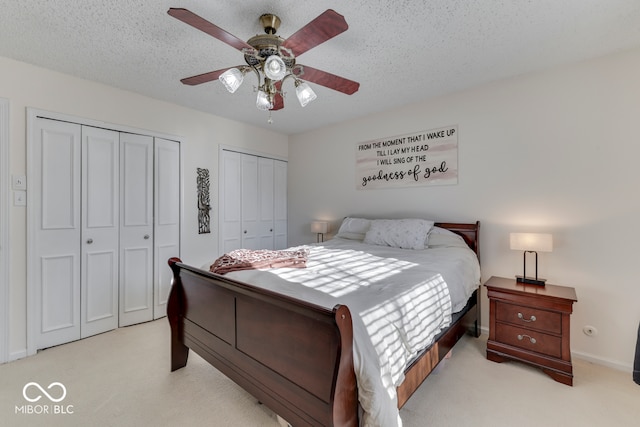 carpeted bedroom with ceiling fan, two closets, and a textured ceiling