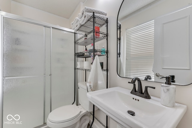 bathroom with an enclosed shower, sink, and toilet