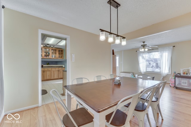 dining area featuring ceiling fan, light hardwood / wood-style floors, and a textured ceiling