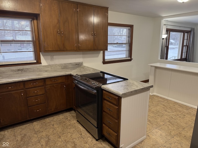 kitchen with stainless steel range with electric stovetop, dark brown cabinets, and kitchen peninsula