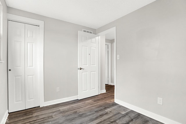 unfurnished bedroom with a closet and dark wood-type flooring