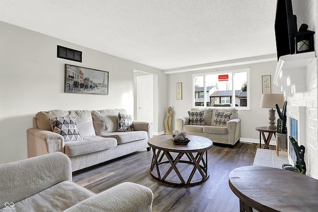 living room featuring a fireplace, dark hardwood / wood-style flooring, and a textured ceiling