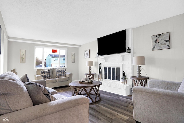 living room with a textured ceiling, dark hardwood / wood-style flooring, and a fireplace