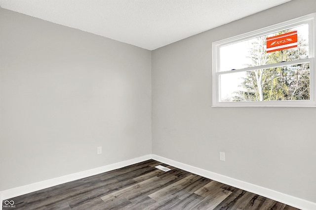 spare room with dark wood-type flooring and a textured ceiling