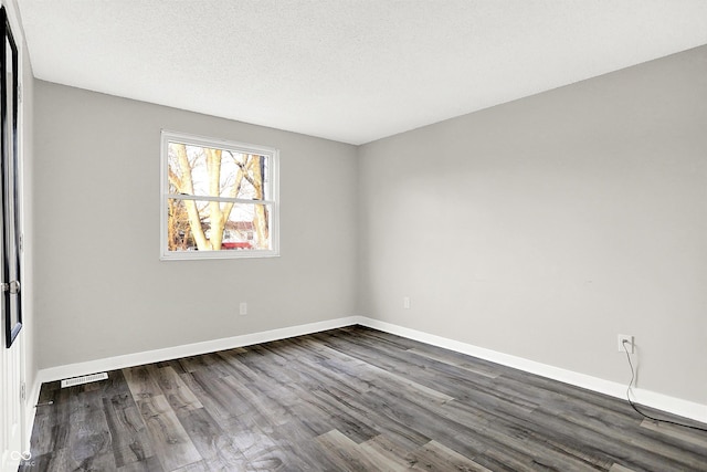 empty room featuring a textured ceiling and dark hardwood / wood-style flooring