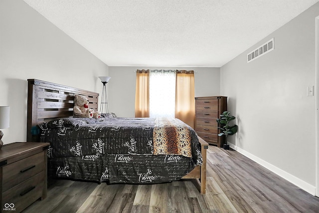 bedroom with wood-type flooring and a textured ceiling