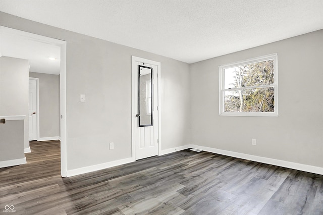 unfurnished room with a textured ceiling and dark wood-type flooring