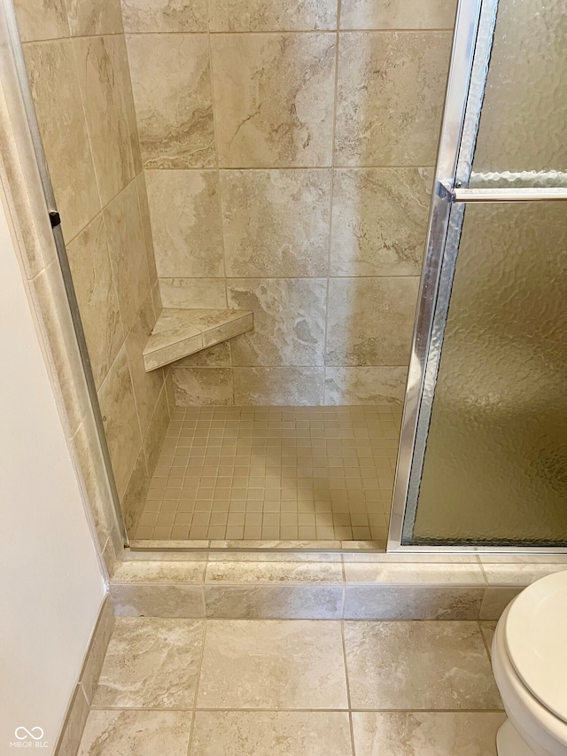 bathroom with a shower with door and toilet