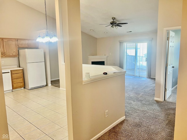 kitchen with light brown cabinetry, decorative light fixtures, light carpet, white appliances, and ceiling fan with notable chandelier