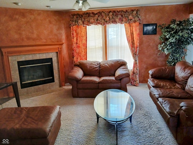 carpeted living room with a tiled fireplace and ceiling fan