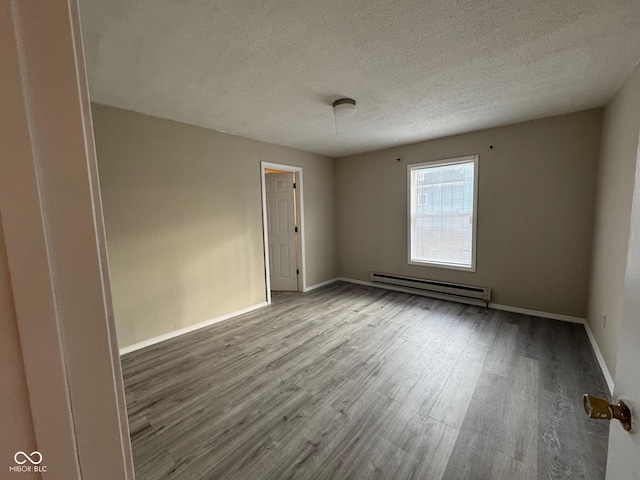 empty room featuring light hardwood / wood-style floors, a textured ceiling, and a baseboard heating unit