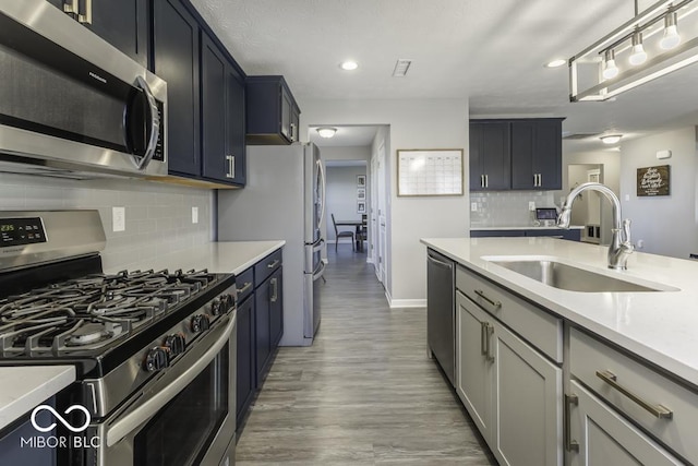 kitchen with light wood-type flooring, decorative backsplash, appliances with stainless steel finishes, and sink