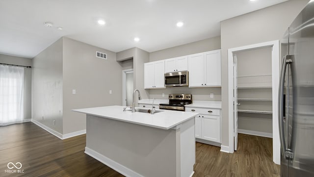 kitchen with sink, dark wood-type flooring, a center island with sink, white cabinets, and appliances with stainless steel finishes