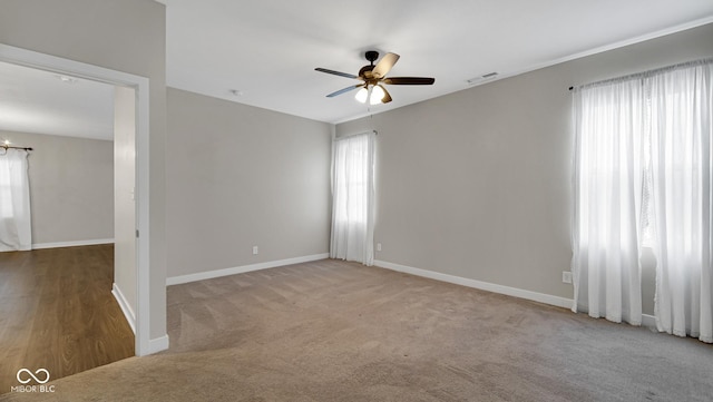 spare room with ceiling fan, plenty of natural light, and light colored carpet