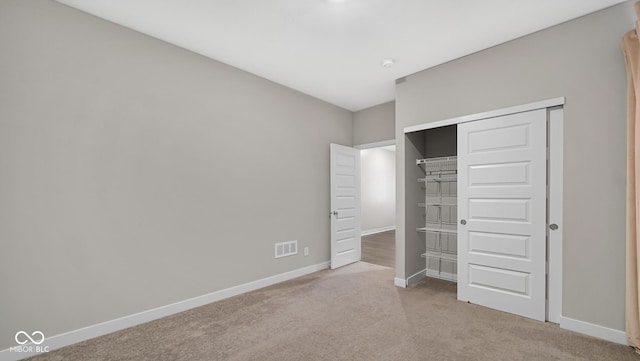 unfurnished bedroom with light carpet and a closet