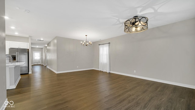 unfurnished living room with plenty of natural light, a chandelier, and dark hardwood / wood-style floors