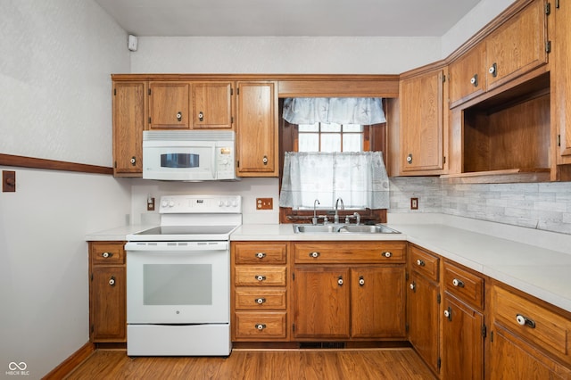 kitchen with white appliances, light hardwood / wood-style floors, sink, and backsplash