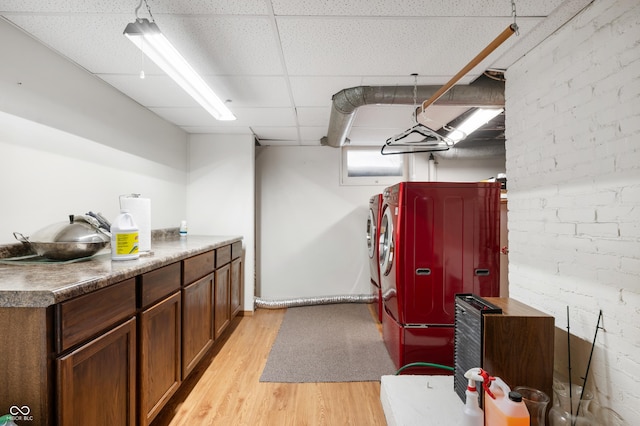 kitchen featuring a drop ceiling, washer and clothes dryer, stainless steel refrigerator, and light wood-type flooring