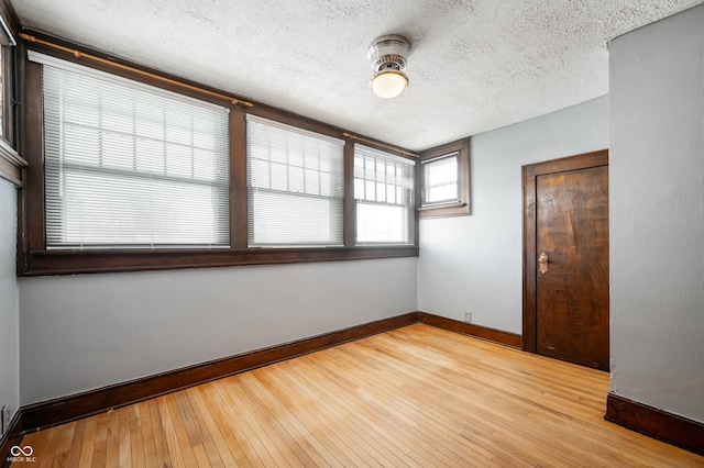 empty room featuring a textured ceiling and light hardwood / wood-style flooring