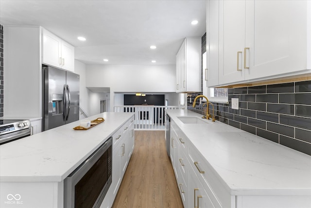 kitchen featuring light stone countertops, a center island, white cabinets, and appliances with stainless steel finishes