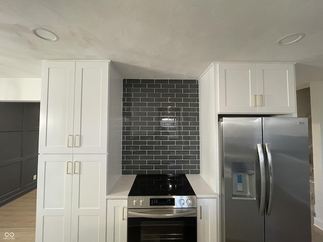 kitchen featuring white cabinets, appliances with stainless steel finishes, light wood-type flooring, and decorative backsplash