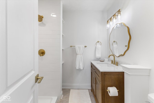 bathroom with tiled shower, tile patterned floors, vanity, and toilet