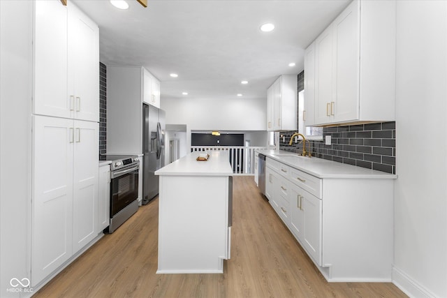 kitchen featuring stainless steel appliances, a kitchen island, white cabinetry, and sink