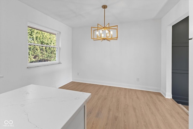 unfurnished dining area featuring a chandelier and light hardwood / wood-style floors