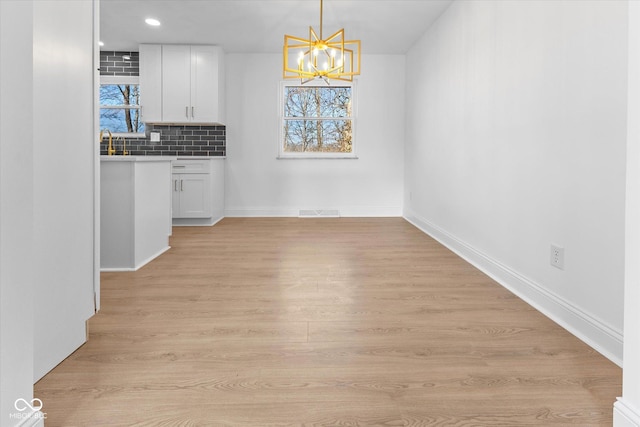 unfurnished dining area featuring light hardwood / wood-style floors and an inviting chandelier