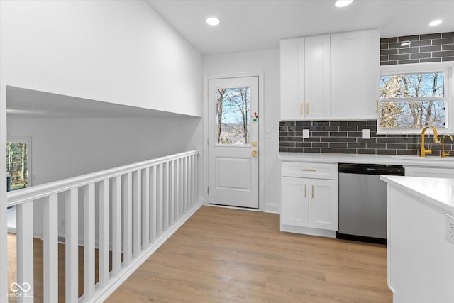 kitchen with white cabinetry, stainless steel dishwasher, tasteful backsplash, and a healthy amount of sunlight