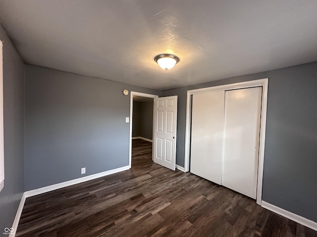 unfurnished bedroom featuring dark hardwood / wood-style flooring and a closet