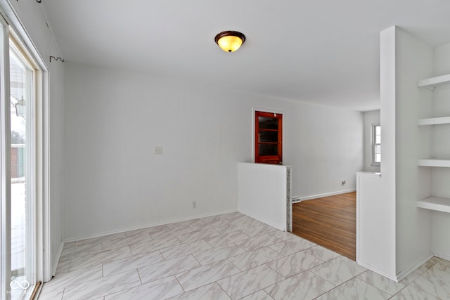 spare room featuring baseboards and built in features