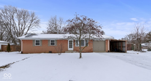 snow covered back of property featuring a garage and brick siding