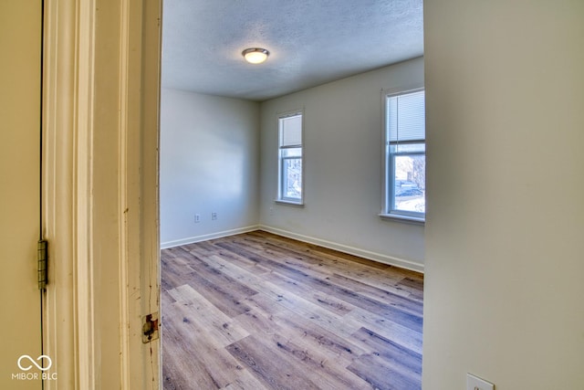 unfurnished room featuring light hardwood / wood-style floors and a textured ceiling