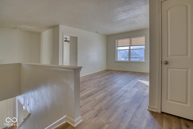 spare room with a textured ceiling and light hardwood / wood-style flooring