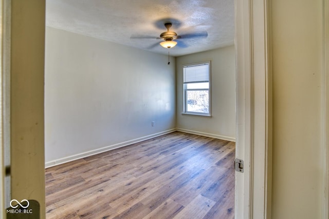 spare room featuring ceiling fan, light wood-type flooring, and a textured ceiling