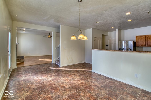 interior space with stainless steel refrigerator with ice dispenser, hanging light fixtures, a textured ceiling, and ceiling fan