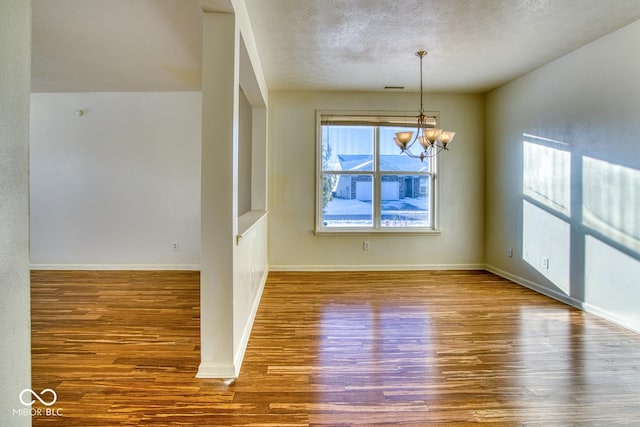 interior space with hardwood / wood-style flooring, a textured ceiling, and a notable chandelier