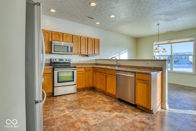 kitchen with sink, pendant lighting, stainless steel appliances, and a textured ceiling