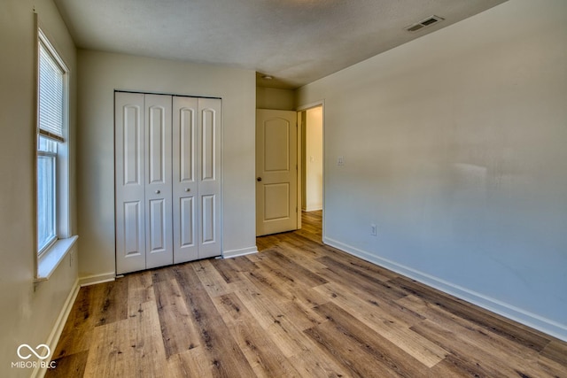 unfurnished bedroom with light wood-type flooring and a closet