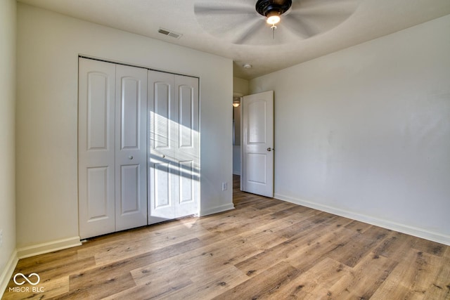 unfurnished bedroom featuring ceiling fan, a closet, and light wood-type flooring