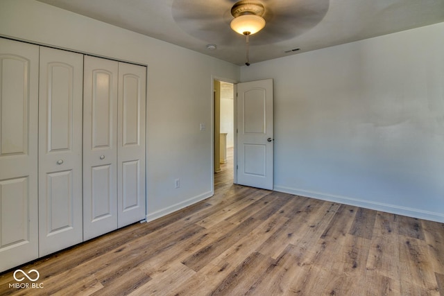 unfurnished bedroom featuring ceiling fan, a closet, and light wood-type flooring