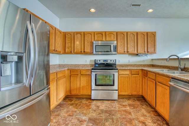 kitchen featuring a textured ceiling, stainless steel appliances, and sink