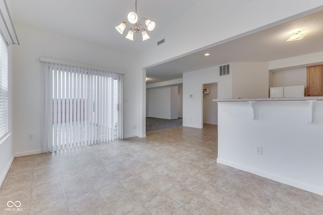 spare room with lofted ceiling and a notable chandelier