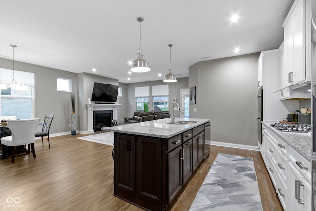 kitchen featuring appliances with stainless steel finishes, dark brown cabinets, sink, white cabinetry, and an island with sink