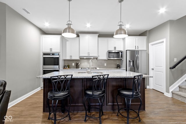 kitchen featuring pendant lighting, a kitchen island with sink, sink, and appliances with stainless steel finishes